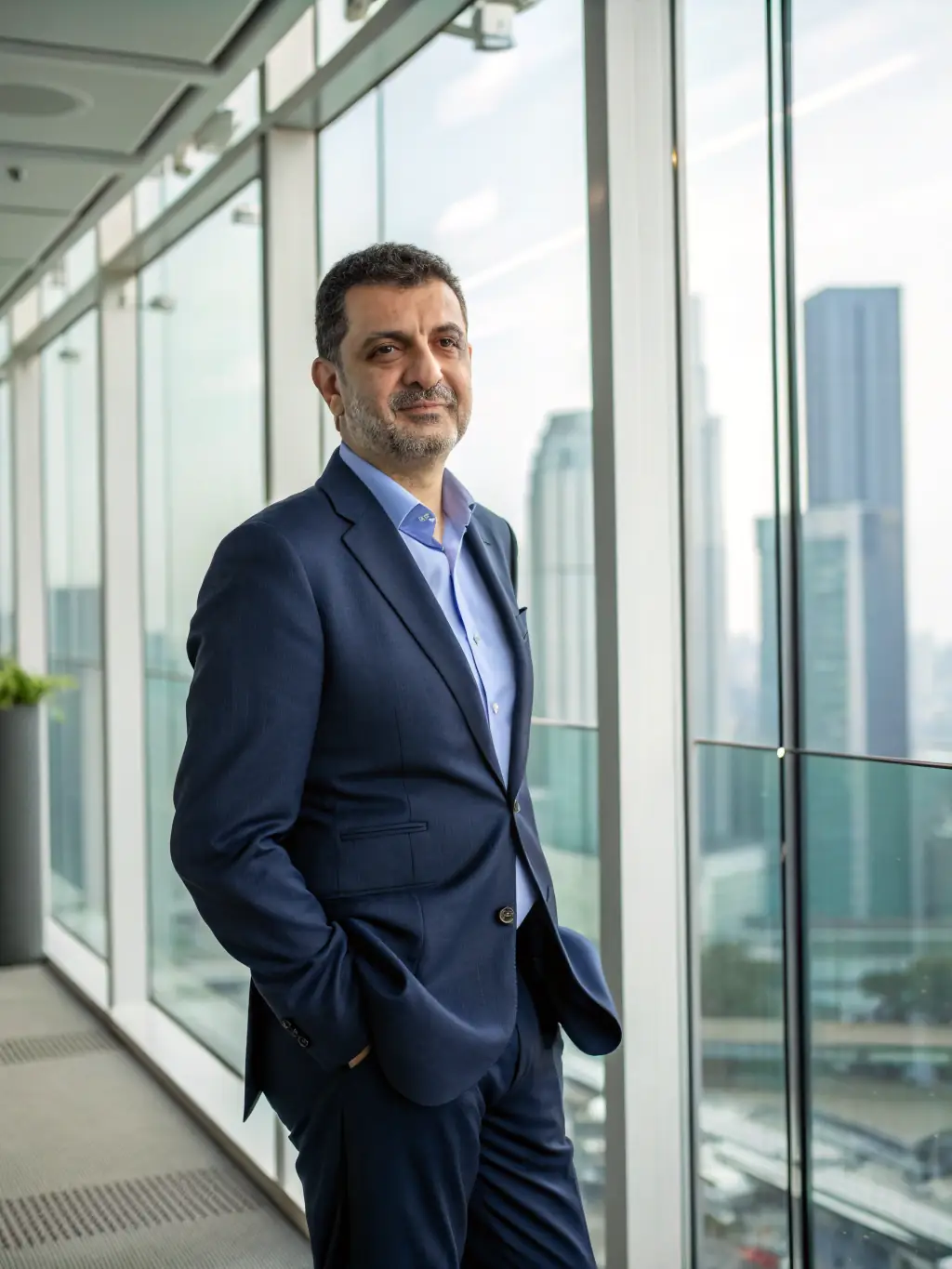 A professional headshot of a mentor, smiling warmly, with a background suggesting a co-working space in Mumbai. The mentor is wearing business casual attire.